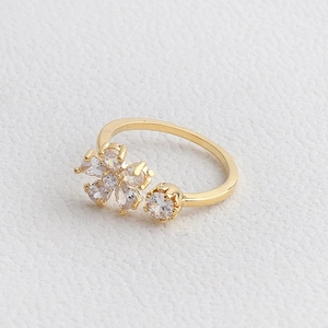 Close-up of golden adjustable ring with flower and rhinestone on white leather