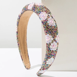 Fashionable padded headband with colorful rhinestones and pink heart charms on a white block
