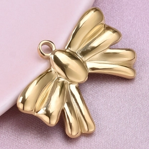 Macro shot of gold-plated 304 stainless steel bow pendant on pink textured fabric