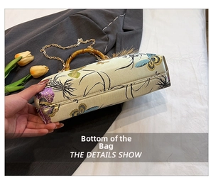 Detailed base view of an embroidered satin bag with bamboo handle and floral patterns
