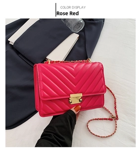 Detail of rose red crossbody bag with V-shaped quilting and gold metal twist lock