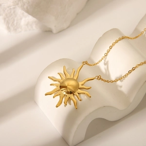 Detailed close-up of a golden sun pendant necklace on a clean white aesthetic background