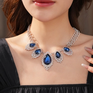 Detail of silver necklace with blue teardrop stones and diamonds on woman's neckline