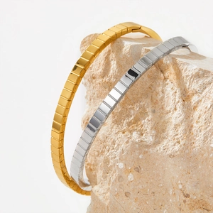 Bracelets rayés polis en or et argent présentés sur une pierre naturelle minimaliste
