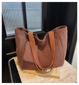 Detail of rust red woven tote bag set with matching pouch on marble surface