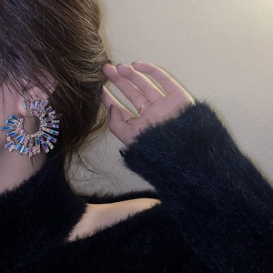 Detail of colorful crystal fan-shaped earrings on a model with golden metal backing