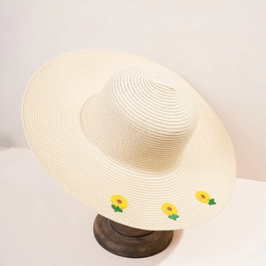Dettaglio del cappello in paglia beige con ricamo a girasole giallo sulla tesa larga