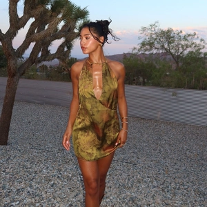 Detail of green floral halter dress with open back and silky satin texture in desert