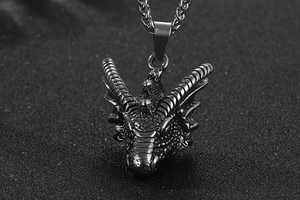 Vue macro d'un pendentif tête de dragon argenté montrant des détails métalliques
