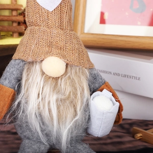 Detail of a brown knitted gnome with white beard and grey felt body for Christmas decor
