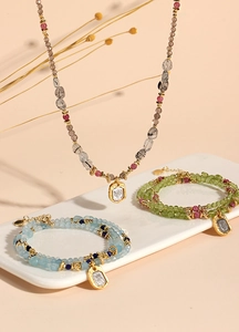 Detailed view of peridot tourmaline and aquamarine beaded jewelry set on white tray