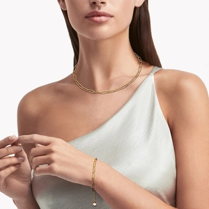 Ensemble collier et bracelet trombone doré avec zircons porté par un mannequin