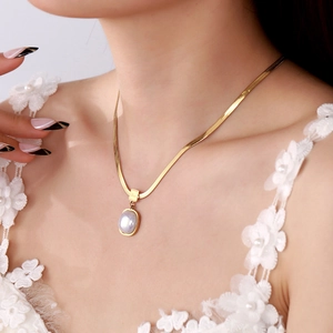 Detail of 18K gold snake chain necklace with an elegant oval pearl pendant on a model