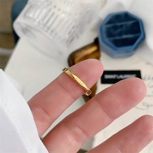 Close-up of golden twisted ring with Je t'aime engraving on a polished finish