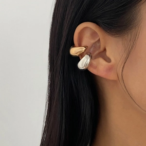 Détail de manchettes d'oreille gouttes métalliques en or et argent portées par un mannequin
