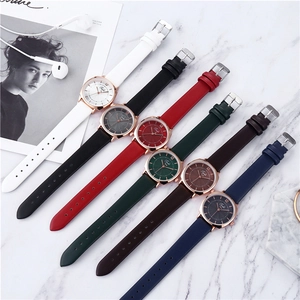 Flat lay of multiple colorful square leather strap watches on marble background