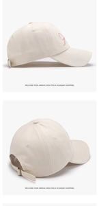 Detail of cream baseball cap featuring pink bow embroidery and adjustable metal buckle