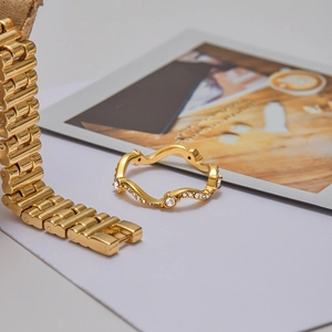 Détail d'une bague dorée ondulée avec strass et d'un bracelet gourmette audacieux