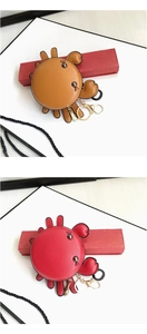Detail showing orange and red leather crab-shaped coin purses with metal keychains