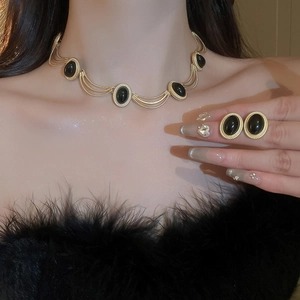 Detail of vintage gold-framed black oval gemstone necklace and earrings on model