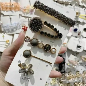 Detail of five-piece hair clip set featuring rhinestones and pearls on display card
