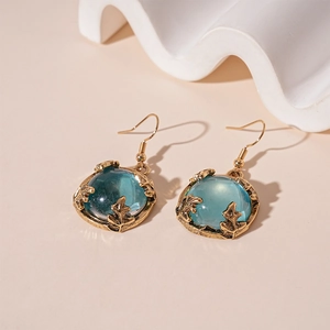 Close-up of vintage gold leaf earrings with round blue translucent resin stones