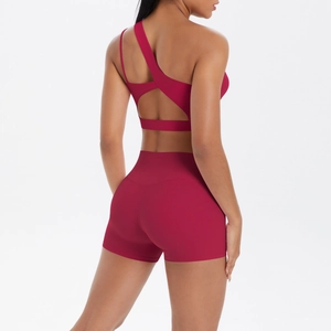 Detail view of burgundy yoga set featuring asymmetric cross-back sports bra and shorts