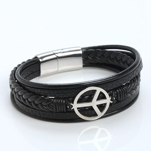 Detail of multi-layer black braided leather bracelet with silver peace symbol and magnetic clasp