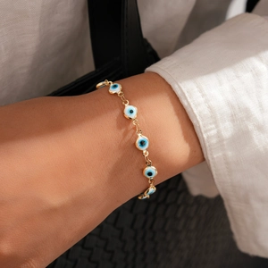 Gros plan d'un bracelet œil porte-bonheur doré porté sur le poignet d'un mannequin