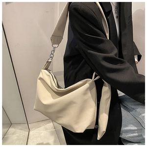 Detail view of beige crossbody bag with silver chain decor on matte leather material