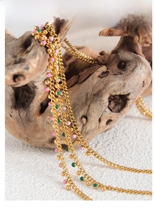 Close-up of golden multi-layer chain necklace with pink and green beads on wood