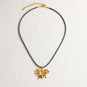 Minimalist 18K gold stainless steel bow pendant necklace with black wax cord on white surface