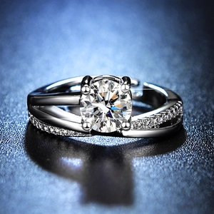 Macro shot of silver moissanite ring with six-prong setting and side diamonds on dark base
