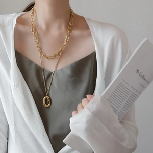 Detail of double-layer gold paperclip chain necklace with irregular oval pendant