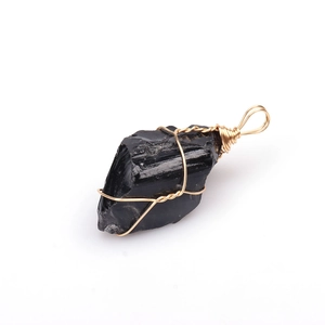 Detail of raw black tourmaline crystal pendant with handcrafted golden wire wrap