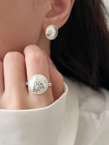Close-up of minimalist silver round hammered ring and stud earring on model