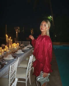 Chic red pleated mini dress with puff sleeves and silver quilted handbag by a pool at night