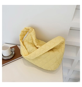 Detail of light yellow quilted dumpling bag with rhombus stitching and soft handle