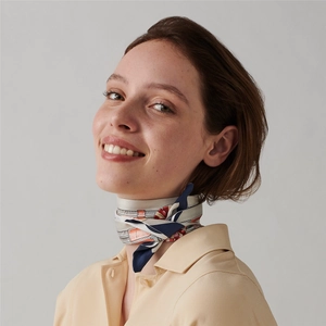 Detail shot of a silk-like floral scarf tied elegantly around the neck of a smiling model