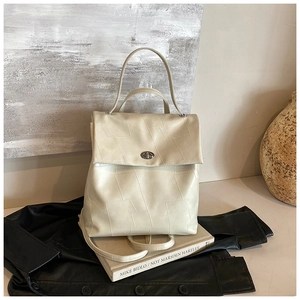 Detailed close-up of cream leather backpack with geometric texture and silver swivel lock
