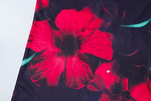 Vue détaillée du motif floral rouge sur un tissu en polyester brillant et fluide