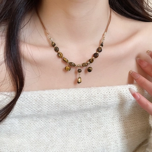 Tiger eye beaded necklace with gold spacers and tassels worn by a model in soft lighting
