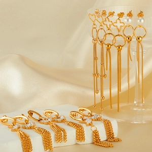 Detailed macro of gold tassel earrings featuring pearl and zircon heart charms
