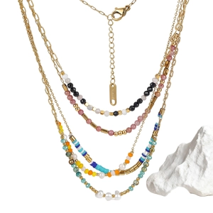 Bohemian multilayered necklace with colorful turquoise beads and gold chains on white stone