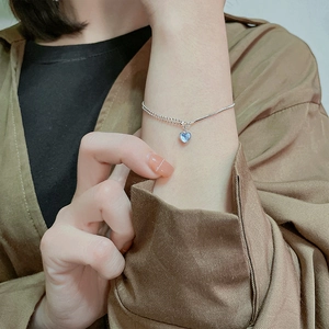Close-up of double-layer silver heart bracelet with light blue gemstone on wrist