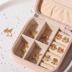 Pink jewelry box organizer showing multiple compartments with gold earrings and pearls