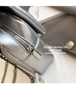 Close-up of the smooth metal zipper and quilted silver PU leather on the square bag