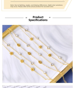 Macro detail of gold flower and heart charms with oval zircon on a layered steel bracelet