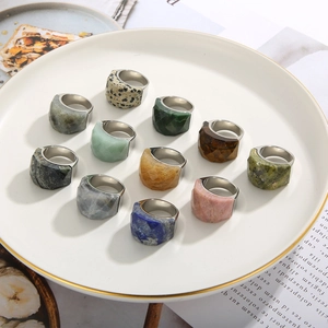 Close-up of assorted natural gemstone rings in silver settings arranged on a tray