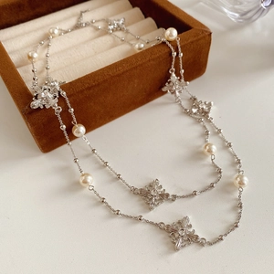 Détail d'un collier de perles argenté avec pendentifs fleurs sur une boîte en velours